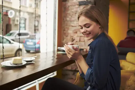 Молодая блондинка с чашкой у окна в кафе