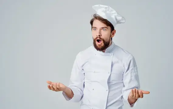 Профессиональный повар жестикулирует руками на светлом фоне, обрезанный вид, модель в головном уборе
