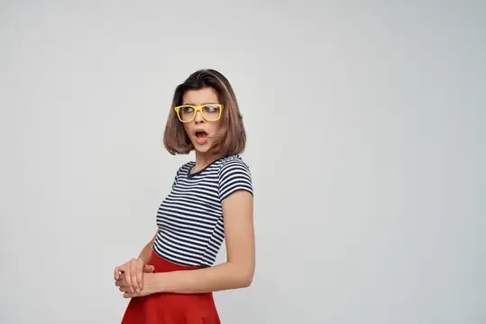 Удивлённая девушка в жёлтых очках и полосатой футболке