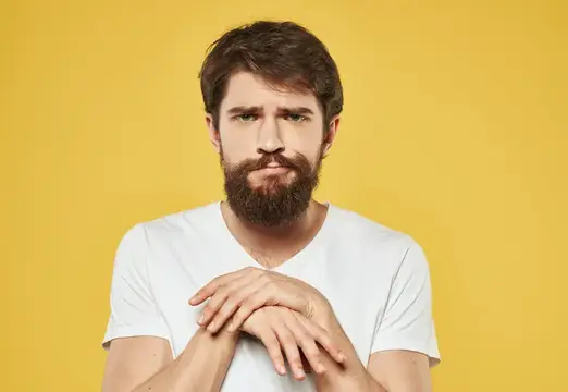 Эмоциональный брюнет жестикулирует руками на жёлтом фоне