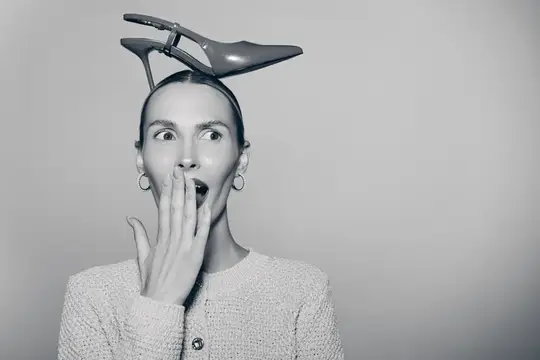 Удивленная женщина с туфлей на голове прикрывает рот рукой