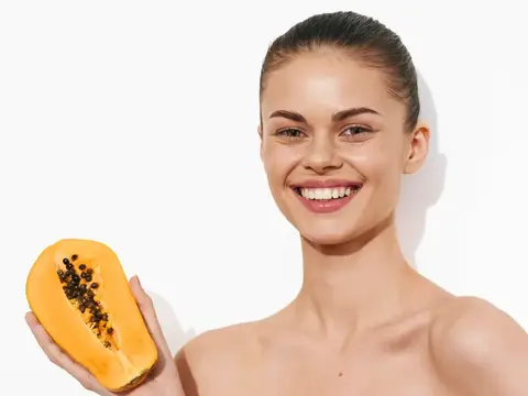 Свежая папайя, которую держит женщина, с долькой спереди на белом фоне