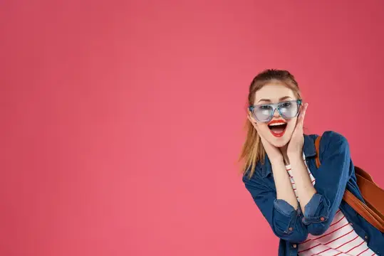 Удивлённая девушка в очках на розовом фоне