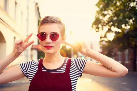 Жизнерадостная женщина в солнцезащитных очках гуляет на улице