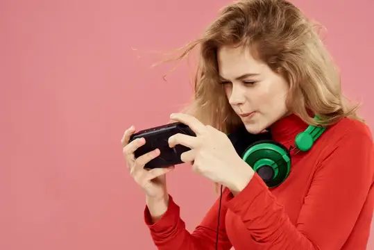 Светловолосая девушка в красном играет в игру на смартфоне