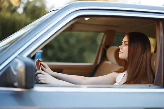 Молодая женщина с телефоном в салоне автомобиля