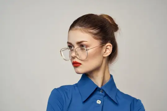 Строгая женщина в очках и голубой рубашке на светлом фоне, портрет, обрезанный вид