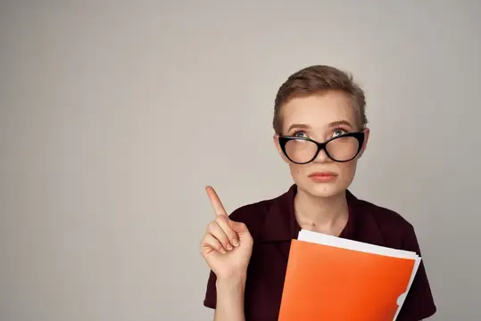 Девушка в очках с папкой поднимает указательный палец вверх