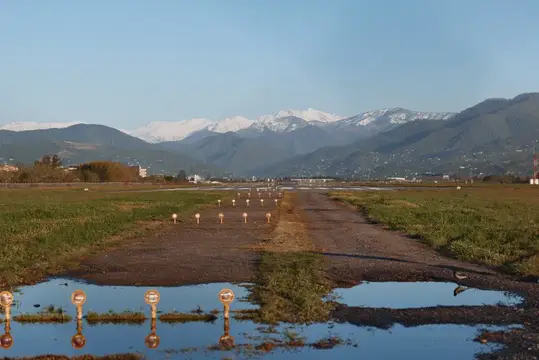 Взлётная полоса с лужами на фоне заснеженных гор