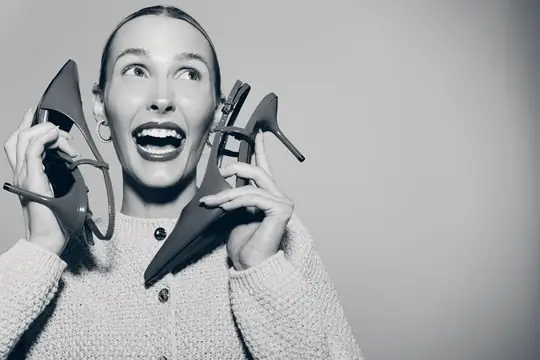 Восторженная женщина с туфлями на каблуках у лица
