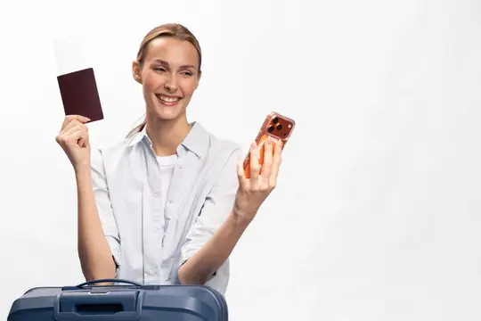 Улыбающаяся светловолосая женщина с паспортом и телефоном у чемодана