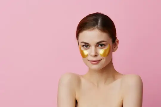 Портрет женщины с золотыми патчами на лице на розовом фоне