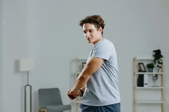 Мужчина тренируется дома с гантелями