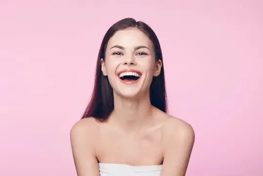 Смеющаяся темноволосая девушка на розовом фоне