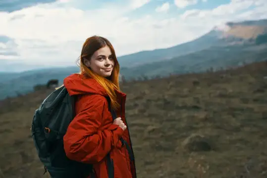 Красивая путешественница с рюкзаком отдыхает в горах на фоне осеннего природного пейзажа