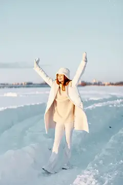Рыжеволосая девушка в белом пальто радуется на льду