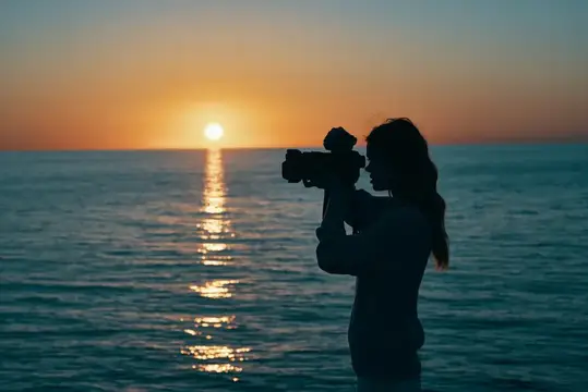 Фотограф с камерой на закате у моря