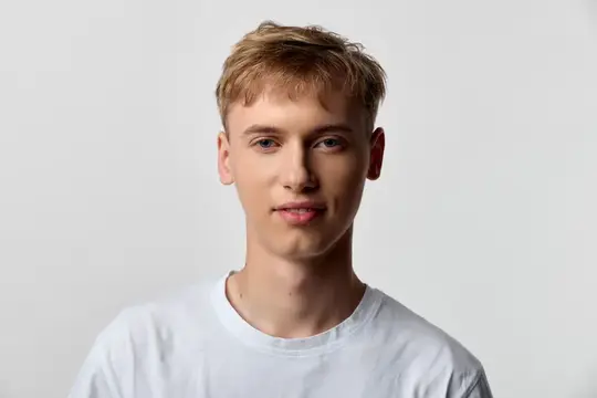 Мужчина-модель в повседневной одежде с расслабленным выражением лица, одетый в белую футболку, стоит на минималистичном фоне, подходит для брендинга, маркетинга или веб-изображений, современный и…