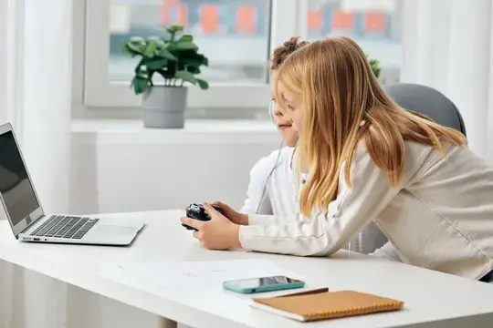 Счастливые мальчик и девочка европейской внешности учатся и играют онлайн дома за своими ноутбуками и планшетами