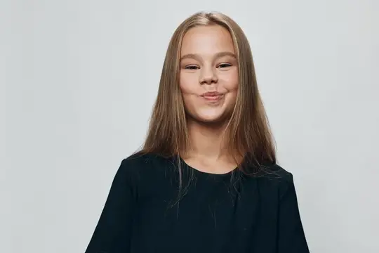 Светловолосая девочка с улыбкой на сером фоне