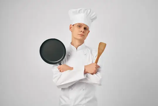 Мужчина в униформе шеф-повара профессионально занимается приготовлением пищи