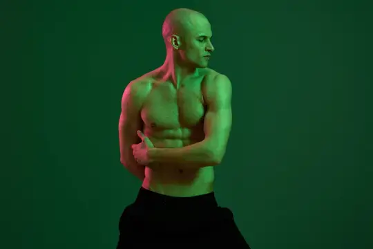 Лысый мускулистый мужчина позирует с зелёной подсветкой