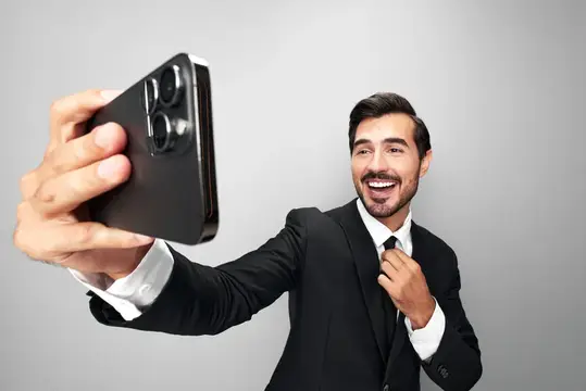 Улыбающийся мужчина в костюме делает селфи на смартфон
