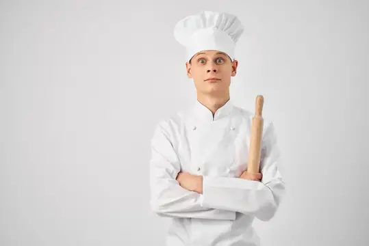 Мужчина в поварской форме, кухонная профессия, работа на светлом фоне