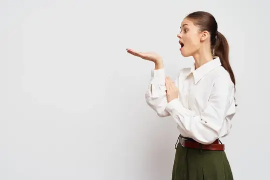 Удивлённая девушка с поднятой ладонью на белом фоне