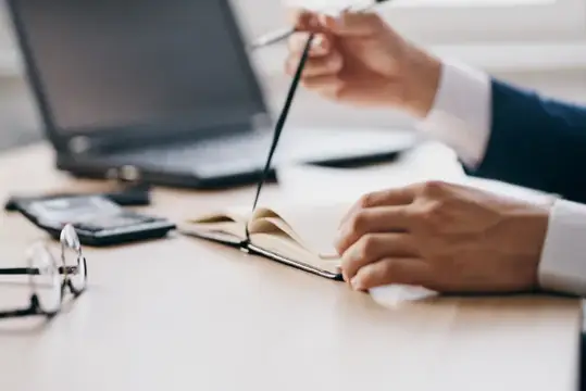 Бородатый мужчина работает за ноутбуком в офисе, испытывая эмоции и используя современные технологии