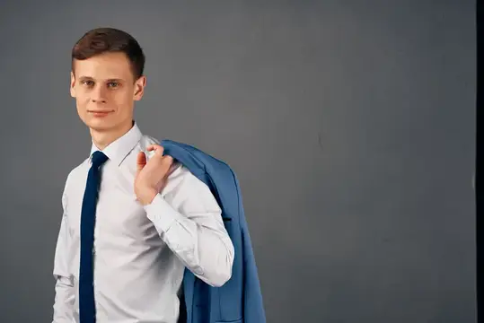 Молодой человек в белой рубашке с пиджаком на плече