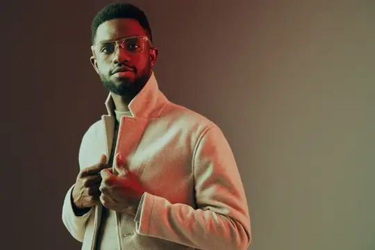 Уверенный темнокожий мужчина в очках и светлом пальто