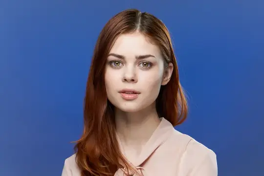 Привлекательная женщина в розовой рубашке, с очаровательным макияжем, крупным планом на голубом фоне