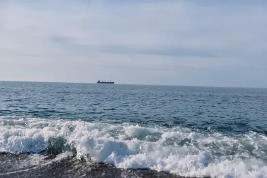 Одинокий грузовой корабль на горизонте спокойного моря
