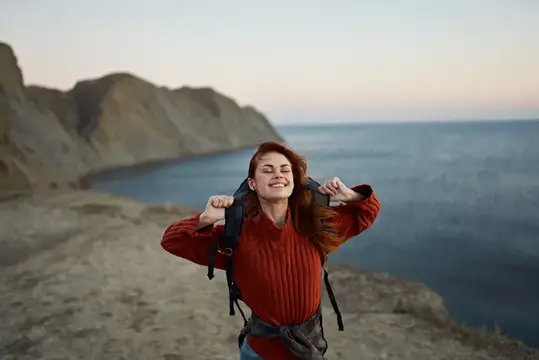 Женщина на фоне осеннего пейзажа: горы, море, пляж, рюкзак