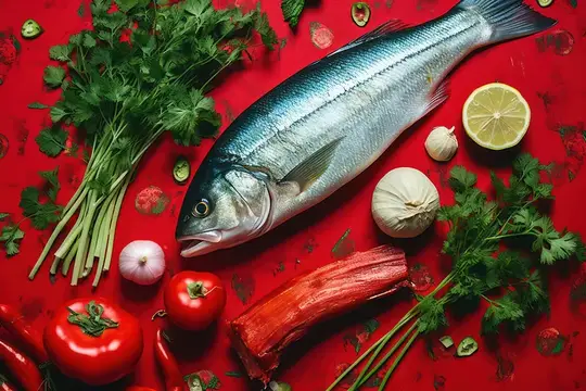 Свежая рыба с зеленью, лимоном и овощами на красном фоне