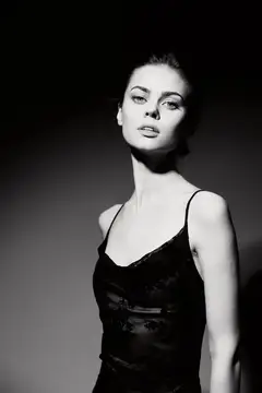 Молодая женщина в чёрном топе на тёмном фоне