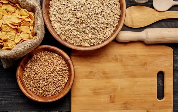 Пшеница на тарелке с кухонной утварью и деревянной доской