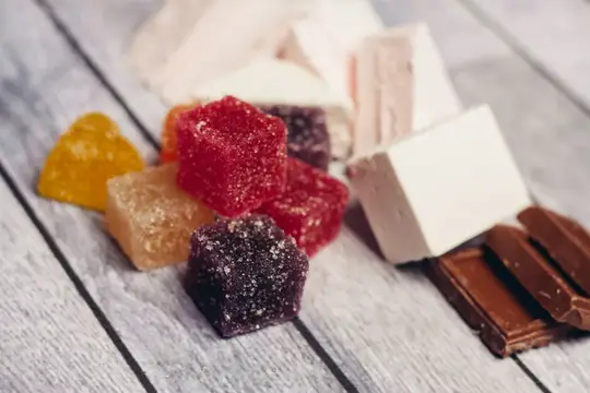 Разноцветные мармеладные кубики и кусочки шоколада на деревянном столе