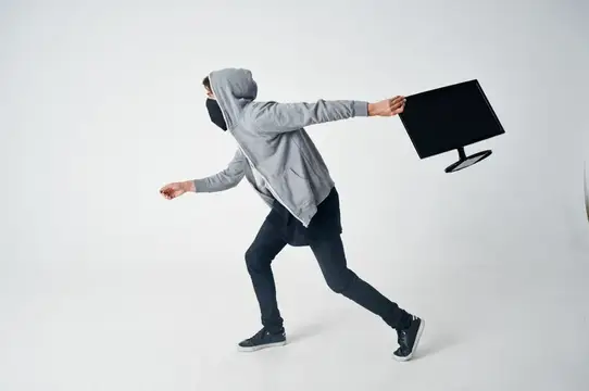 Мужчина в капюшоне и маске убегает с монитором в руке