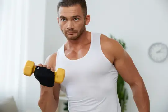 Спортивный мужчина с гантелью тренирует руки дома