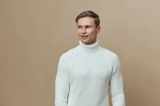 Улыбающийся светловолосый мужчина в белом свитере на бежевом фоне