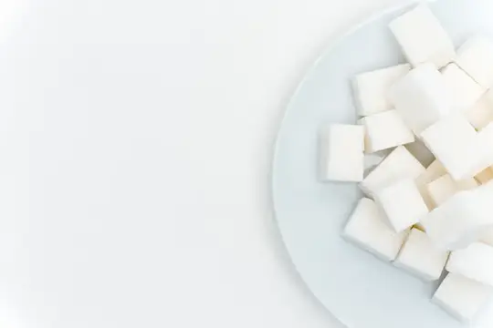 Белые кубики сахара горкой на светлой тарелке