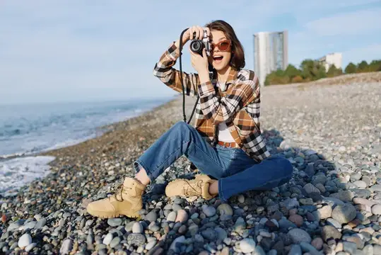 Женщина-фотограф на скалистом берегу с камерой
