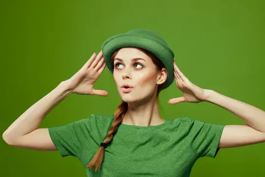Рыжеволосая девушка с косой в зелёном берете и футболке на зелёном фоне