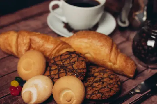 Круассаны и печенье с чашкой кофе на деревянном столе