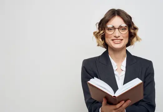 Улыбающаяся женщина в очках с книгой на светлом фоне
