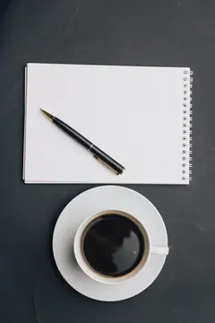 Чашка кофе, блокнот, ручка, очки на рабочем столе