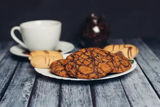Печенье с шоколадной глазурью на тарелке рядом с чашкой кофе