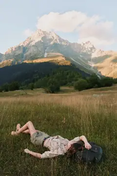 Девушка лежит на траве на фоне горных вершин